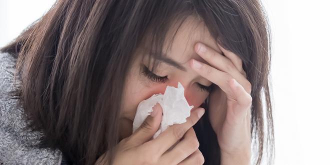 a stressed woman sneezing into a tissue