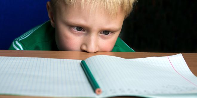 A child staring helplessly at his blank schoolwork