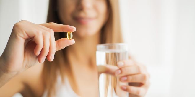 a calm and happy woman taking a capsule of CBD