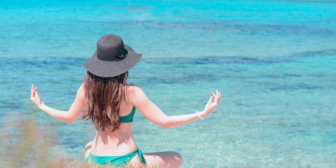 Young woman practices qigong on the beach