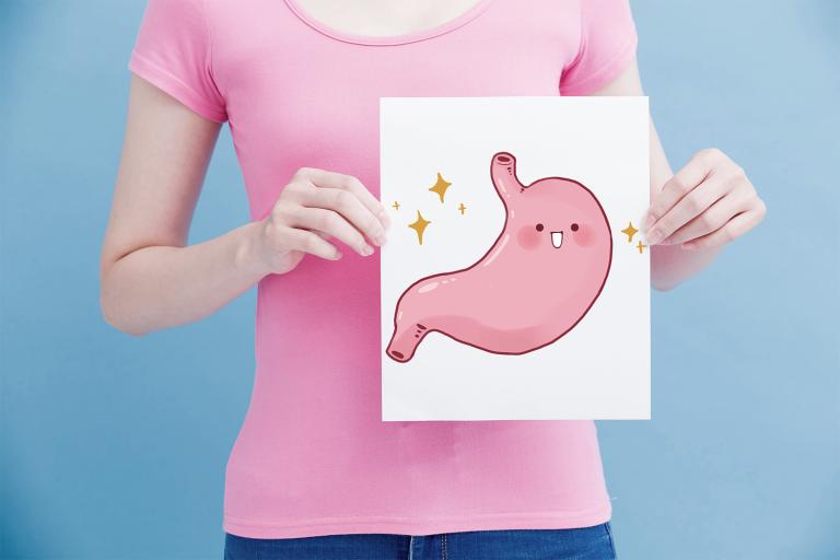 A woman holding an illustration of a happy stomach