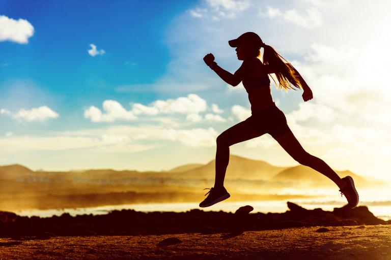 Silhouette of a female athlete runner running in sunset.