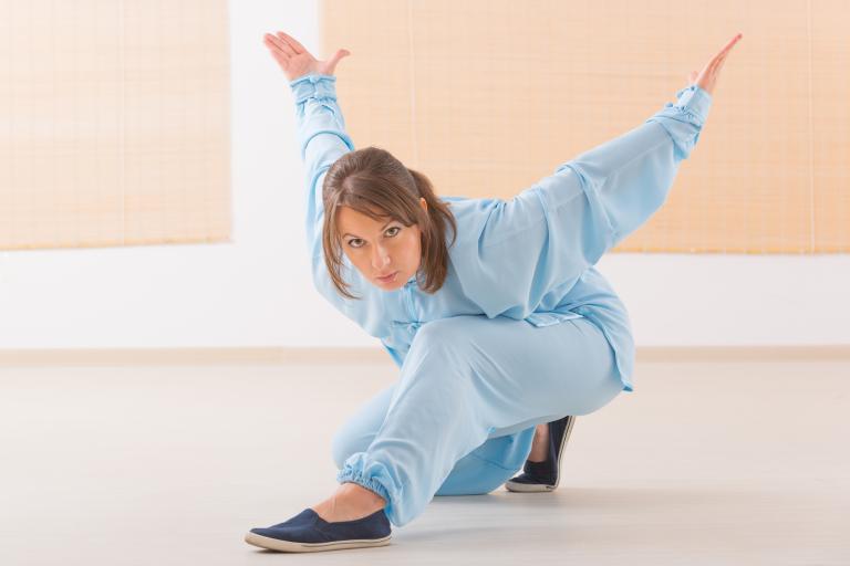 a woman practicing qi gong tai chi in a low position