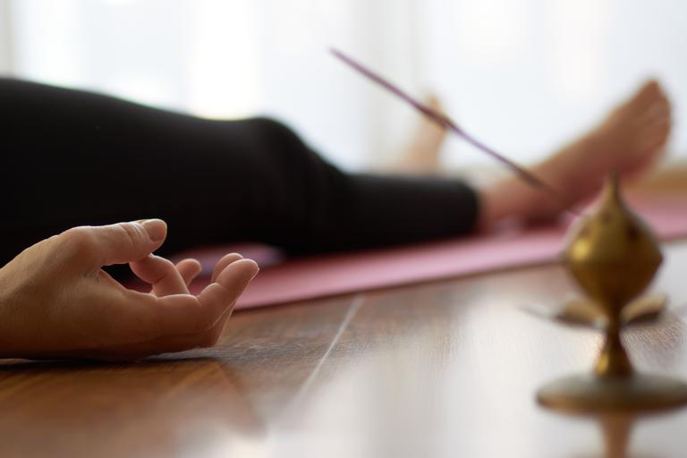 a woman in the yogic corpse pose with incense